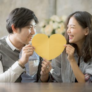 couples of asian man and woman holding heart shape paper cut with happiness emotion ,people love conceptual